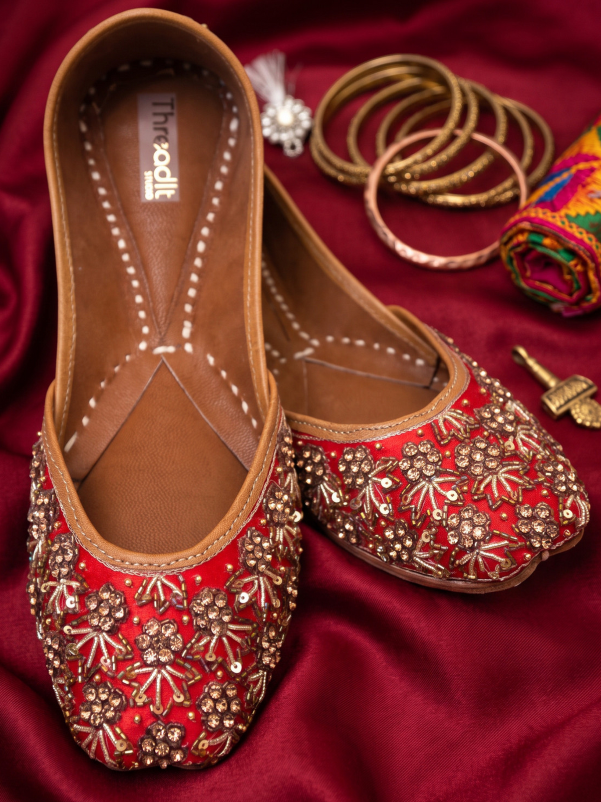 ThreadItStudio red and golden jutti featuring intricate heavy dabka handwork embroidery for weddings and festivals.