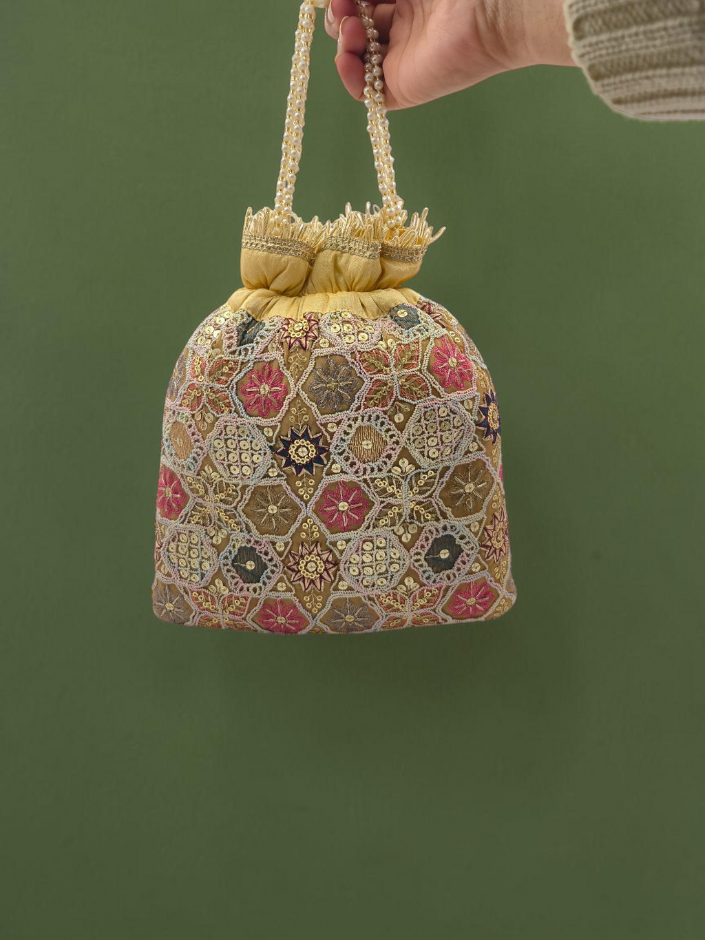 ThreadItStudio peach and golden potli bag with intricate geometric zari embroidery and elegant pearl handle tassels.