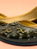 ThreadItStudio brown leather juttis with antique brass camel motifs and metallic studs on a soft pink background