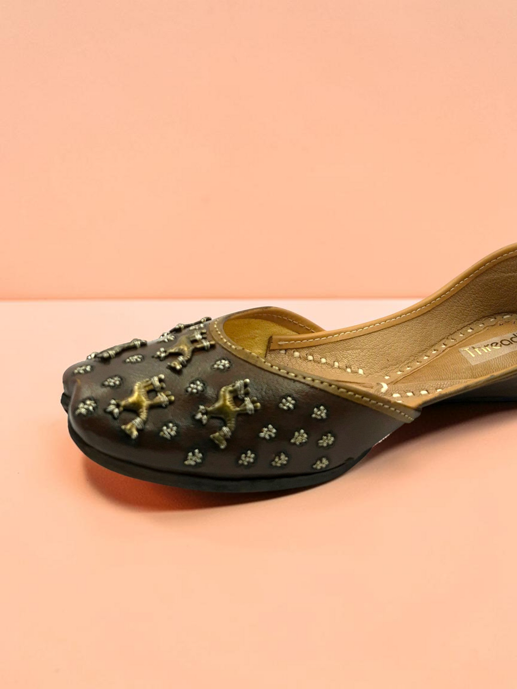 ThreadItStudio brown leather juttis featuring antique brass camel motifs and metallic stud detailing
