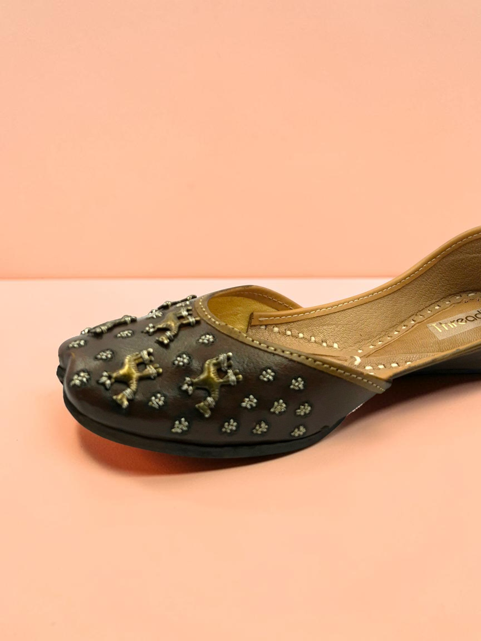 ThreadItStudio brown leather juttis featuring antique brass camel motifs and metallic stud detailing