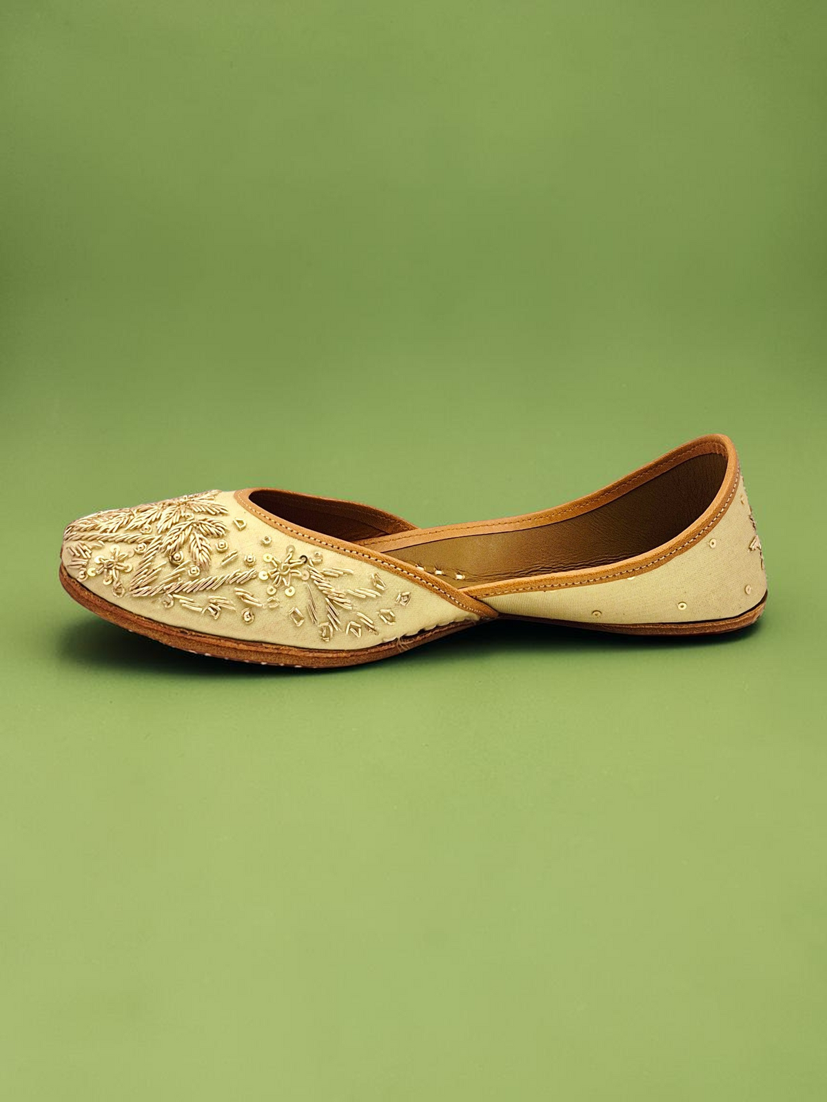 ThreadItStudio handcrafted jutti with intricate golden embroidery on a cream fabric base for festive wear.