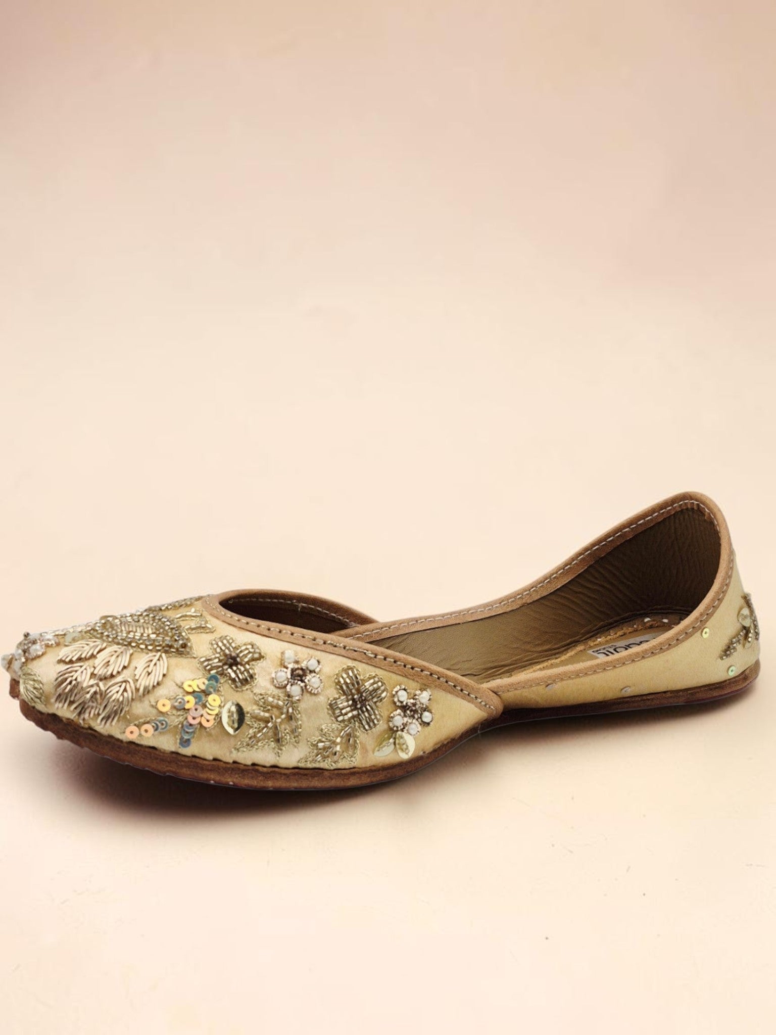 ThreadItStudio handcrafted beige jutti with intricate golden peacock embroidery and sequin detailing for festive wear.