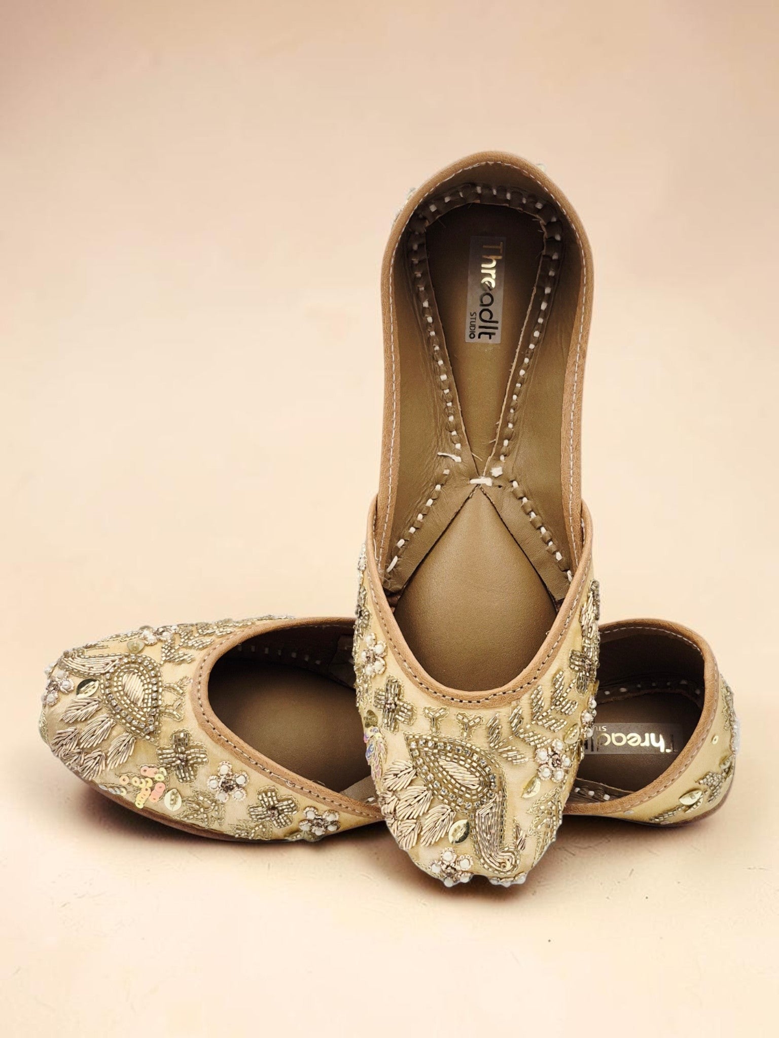 ThreadItStudio handcrafted jutti with intricate golden peacock embroidery and beadwork for festive occasions.