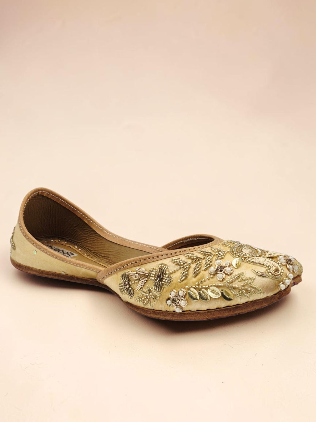 ThreadItStudio handcrafted golden jutti with intricate peacock embroidery and traditional beadwork for festive wear.