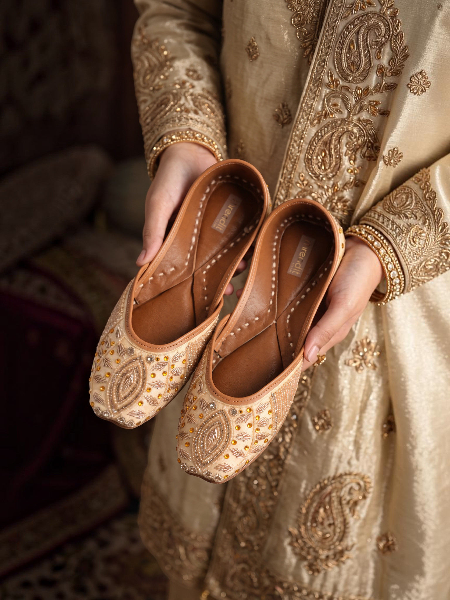 ThreadItStudio Honey Glow Steps handcrafted juttis with intricate gold embroidery and beadwork held in hands