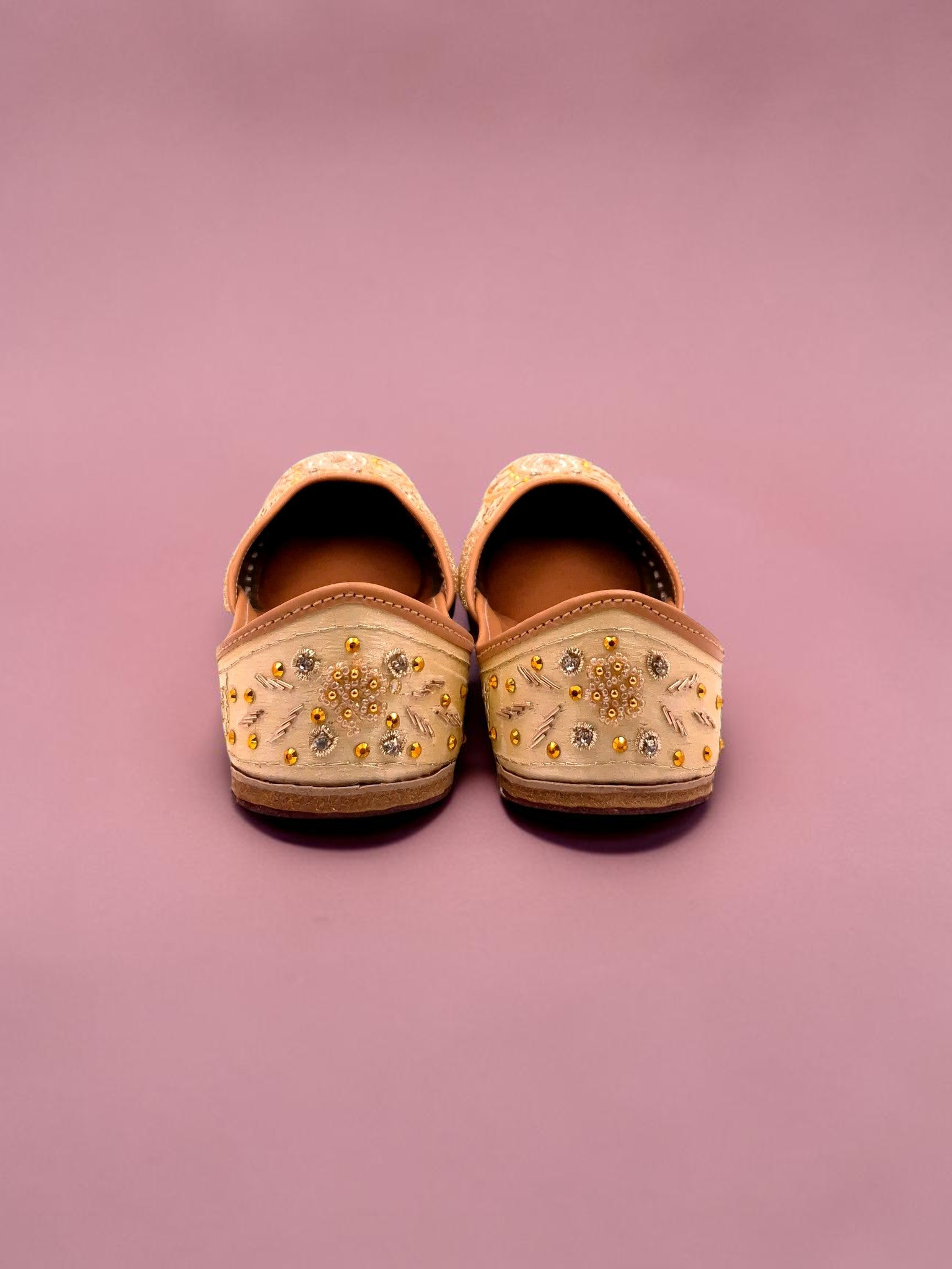 ThreadItStudio Honey Glow Steps handcrafted juttis with intricate gold embroidery on a soft beige fabric background.