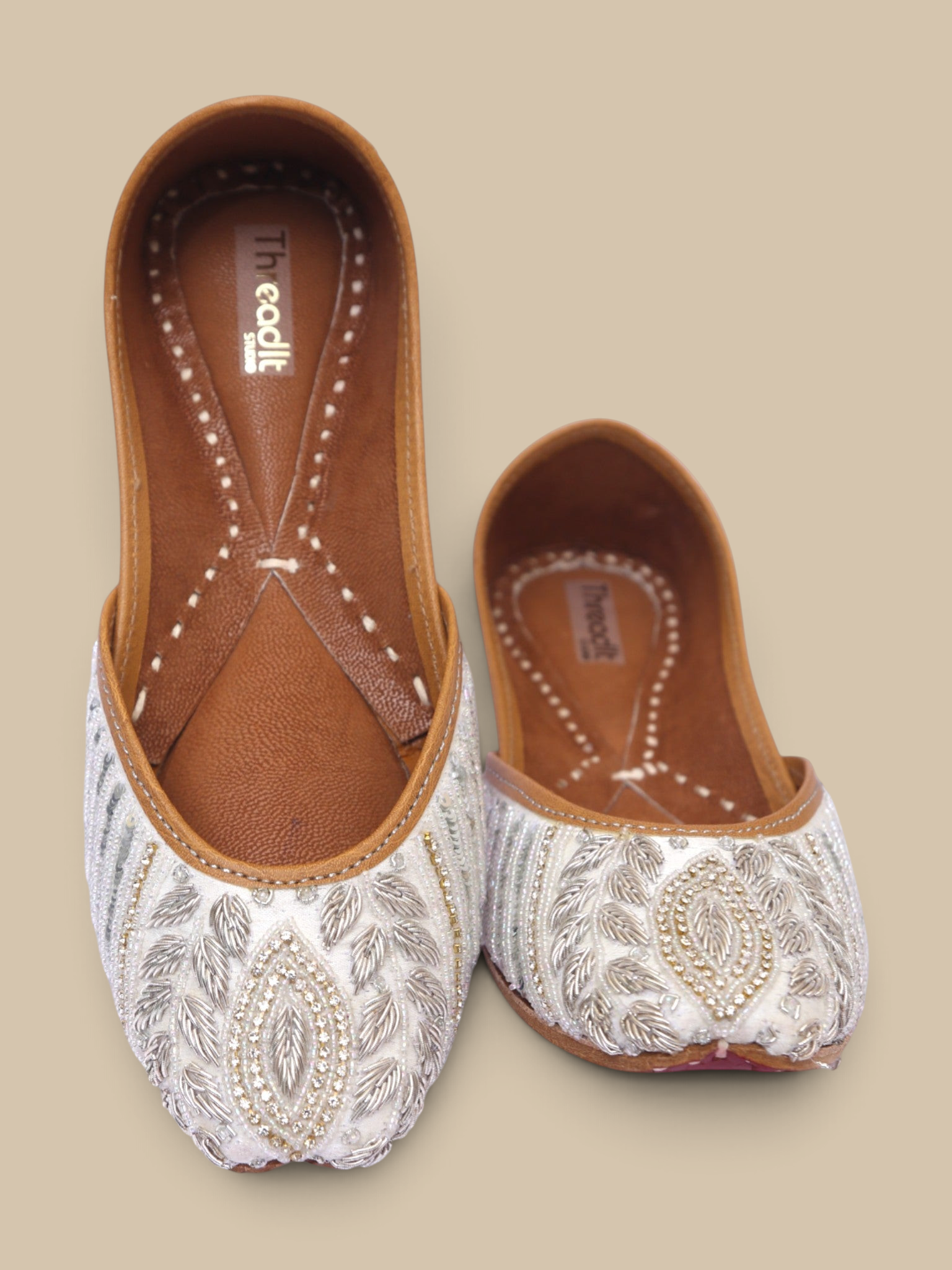 ThreadItStudio ivory juttis featuring delicate silver petal embroidery and intricate floral needlework details.