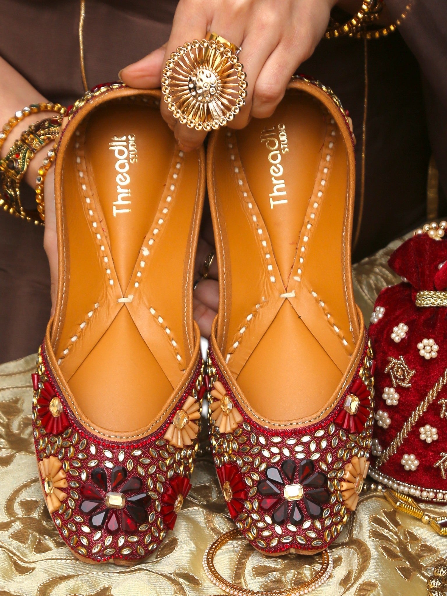 ThreadItStudio handcrafted ethnic jutti featuring intricate red and gold kundan beadwork for weddings and festivals.