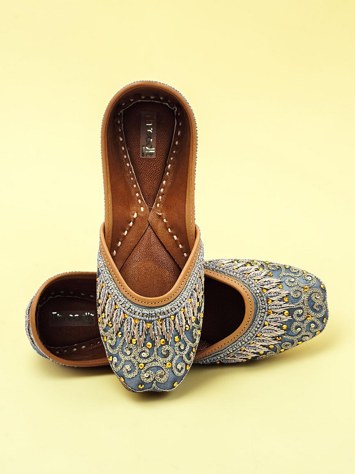 ThreadItStudio handcrafted midnight blue jutti with intricate gold eagle embroidery and traditional artisanal details.