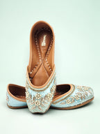 ThreadItStudio sky blue handcrafted ethnic jutti with intricate floral embroidery and pearl detailing on a blue background