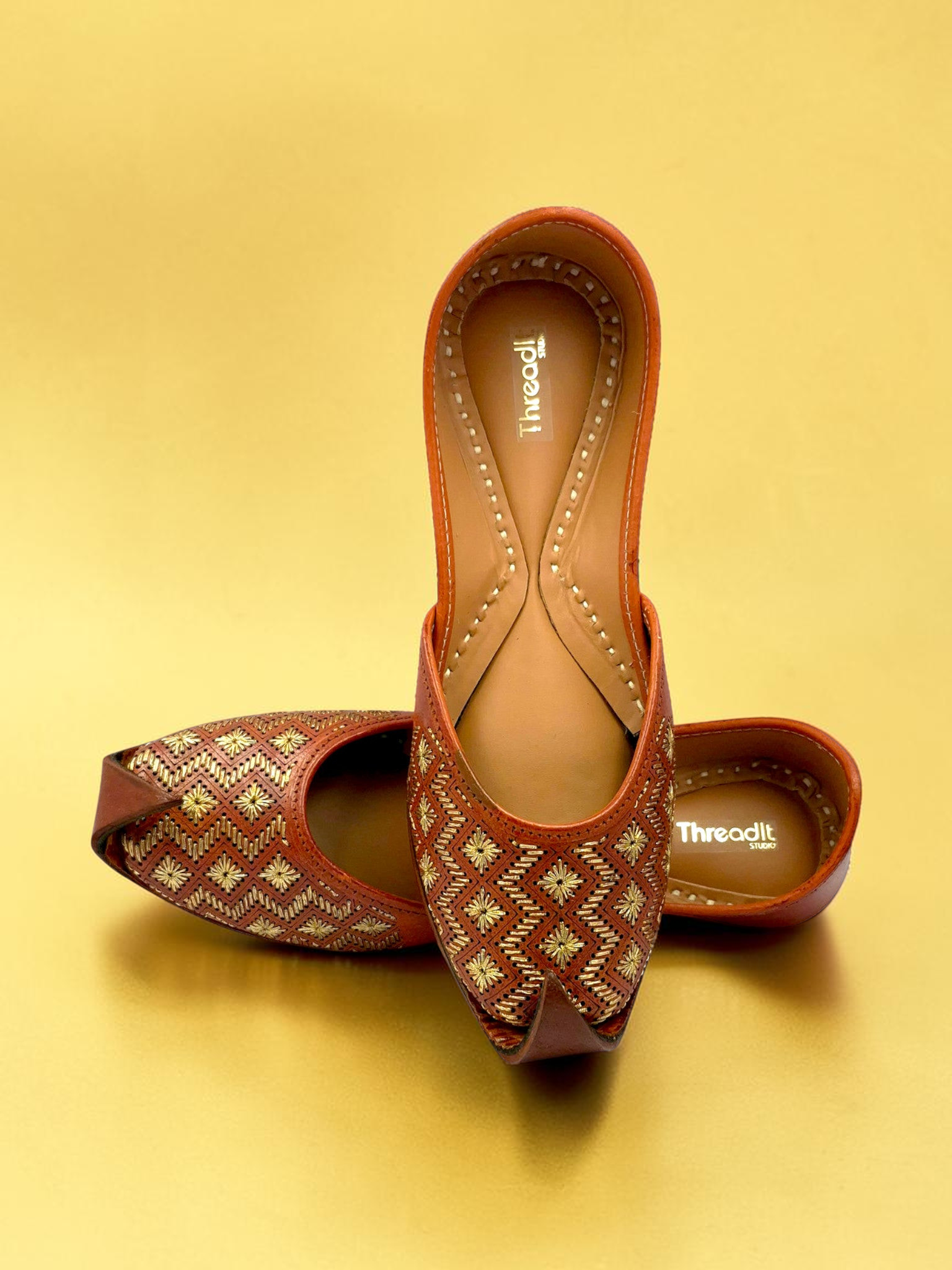 ThreadItStudio tan-brown leather juttis with gold-thread geometric embroidery and starburst floral motifs