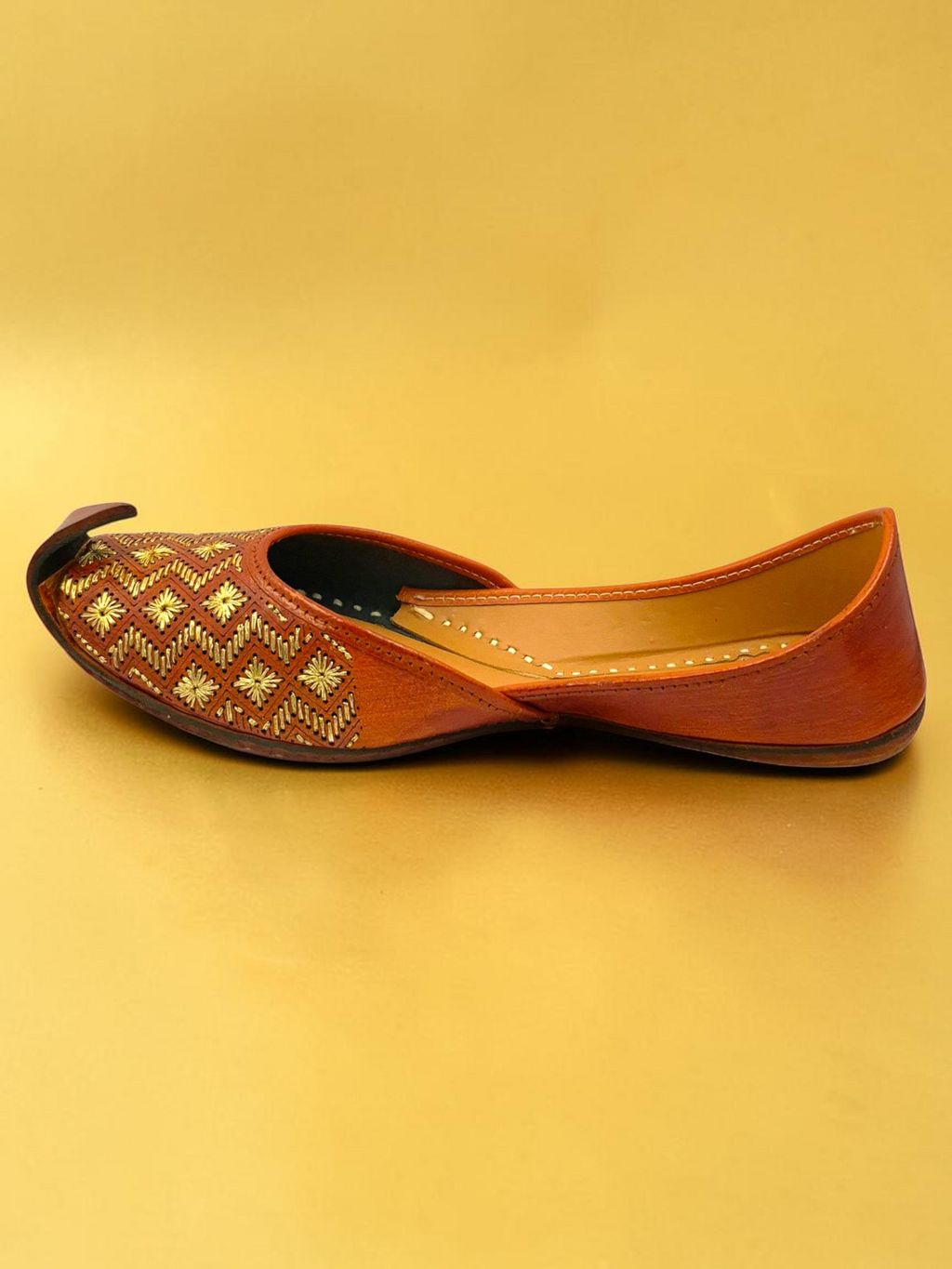 ThreadItStudio Virsa Walk tan leather jutti with gold geometric and floral embroidery on a gold background